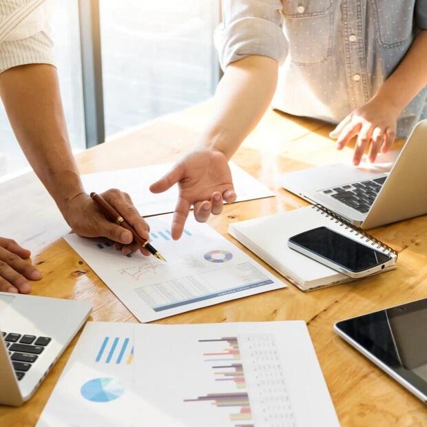 Photo d'une réunion avec focus sur la table sur laquelle sont posés des ordinateurs, ordinateurs et documents..